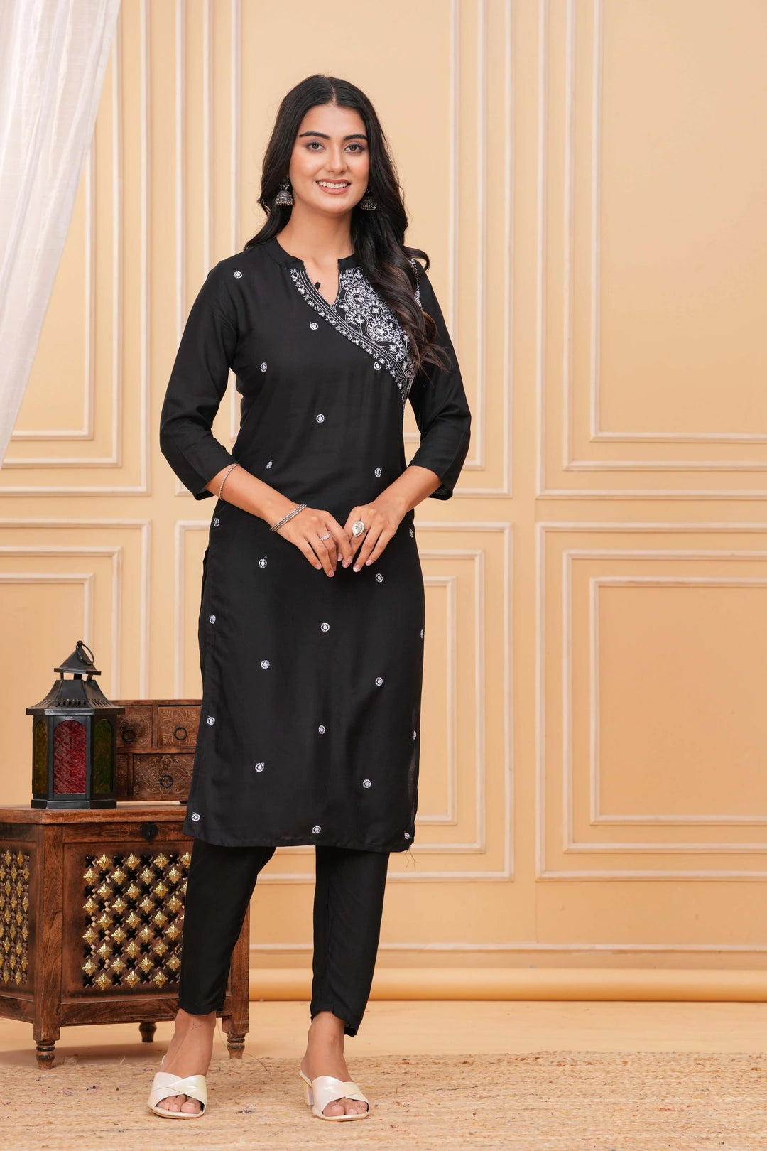 Black rayon blend suit set featuring a kurta with white intricate angrakha-style embroidery on the yoke and scattered circular motifs, paired with black pants.
