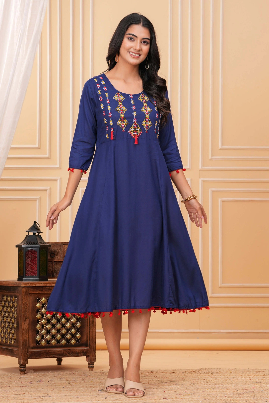 Royal blue rayon A-line kurti with multi-colored thread embroidery on the yoke and red tassel detailing on sleeves and hem.
