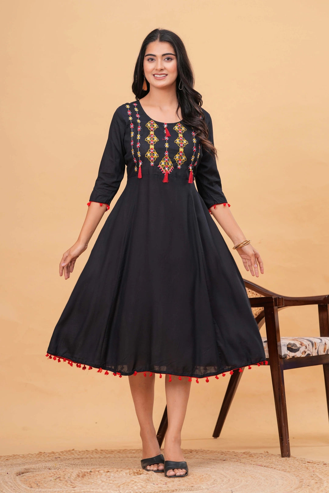 Black rayon flared kurti dress with multi-color embroidery on yoke and red pom-pom tassels on sleeves and hem