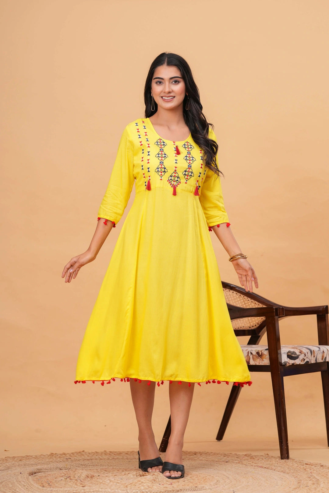 Sunshine yellow rayon Anarkali kurta with blue and red embroidered geometric patterns and red tassels on neckline, sleeves, and hem