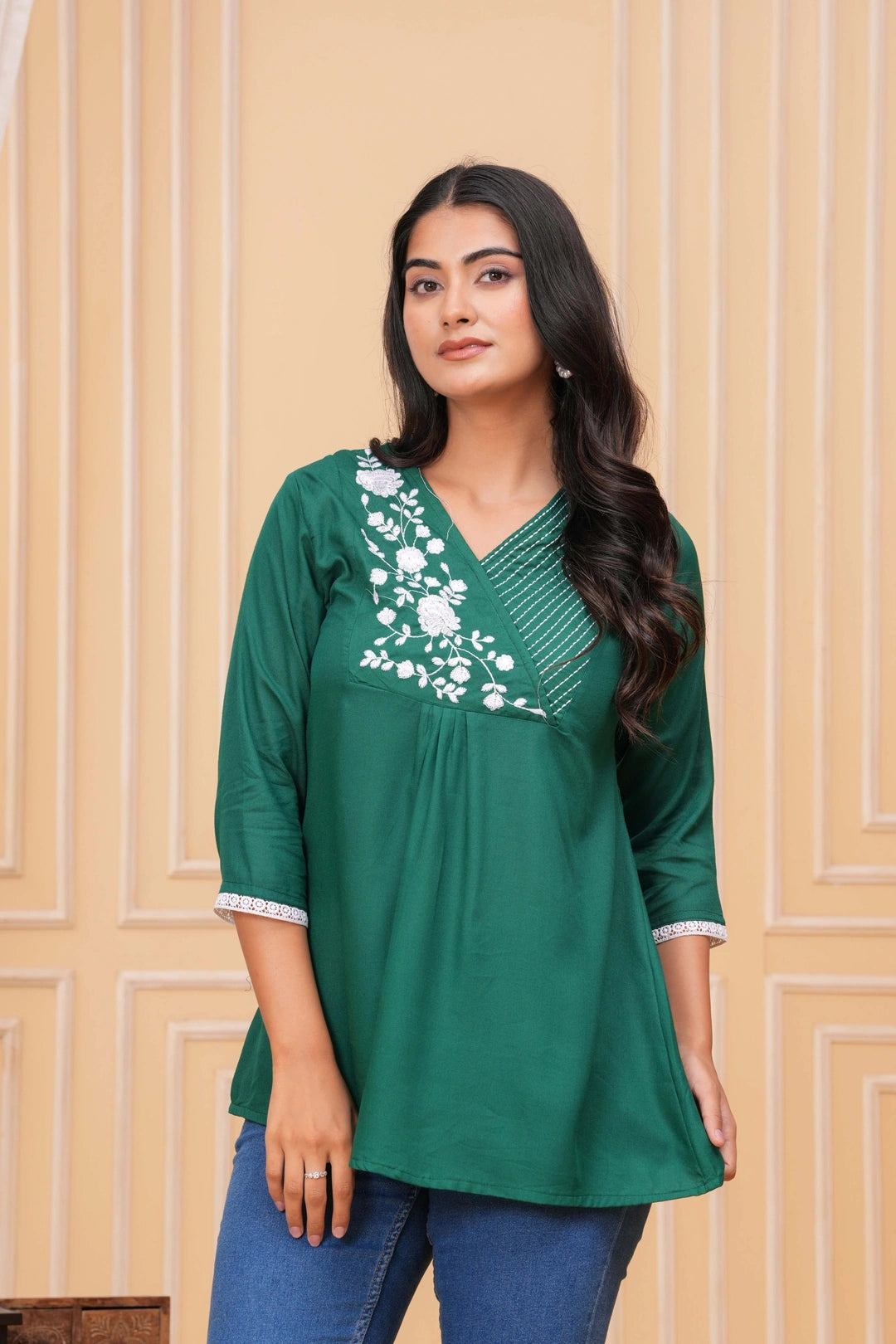 Emerald green cotton tunic featuring white floral embroidery on the V-neck yoke and white lace trim on the sleeves, worn by a model